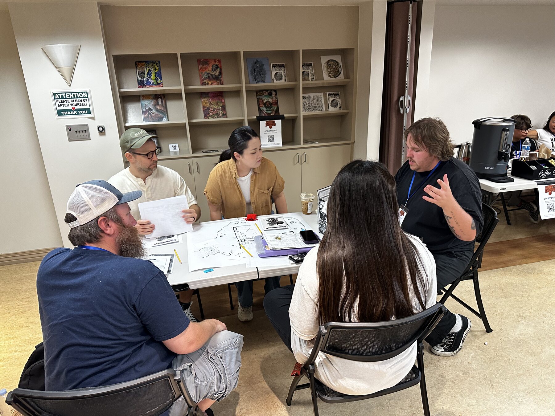 Players seated around a game table at Mighty Deeds Summer 2026